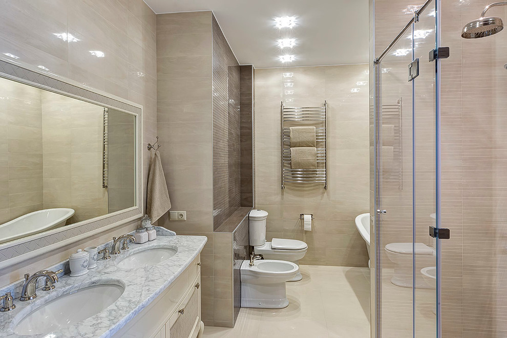 Immagine di una stanza da bagno padronale tradizionale con ante bianche, bidè, piastrelle beige, pareti beige, lavabo sottopiano, top in marmo, doccia ad angolo e porta doccia a battente