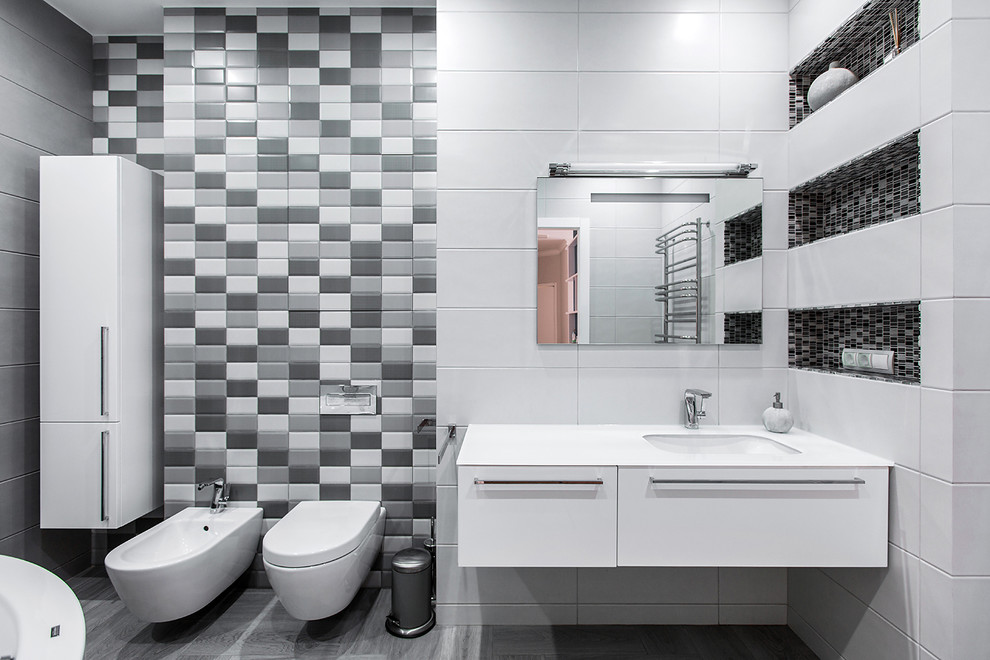 Scandinavian grey and white ensuite bathroom in Moscow with flat-panel cabinets, white cabinets, white tiles, grey tiles, black and white tiles, black tiles, mosaic tiles, a wall mounted toilet, multi-coloured walls and a submerged sink.