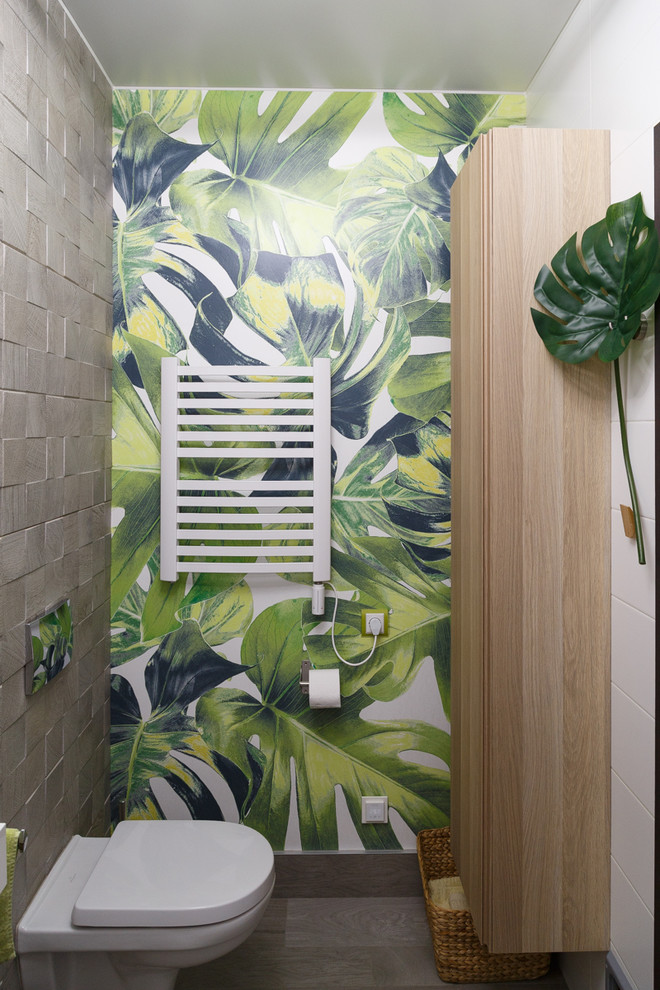 Ejemplo de cuarto de baño principal actual con armarios con paneles lisos, puertas de armario de madera clara, sanitario de pared, lavabo integrado y suelo gris