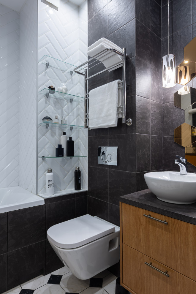 Idéer för att renovera ett mellanstort funkis svart svart badrum med dusch, med släta luckor, skåp i mellenmörkt trä, ett platsbyggt badkar, en dusch/badkar-kombination, en vägghängd toalettstol, svart kakel, ett fristående handfat och flerfärgat golv