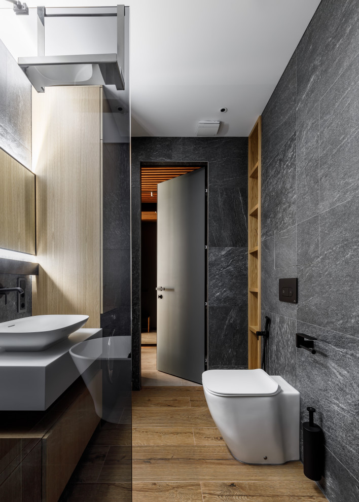 Modernes Badezimmer mit freistehender Badewanne, Nasszelle, schwarzen Fliesen, braunem Boden, WC-Raum und Wäscheaufbewahrung in Sankt Petersburg