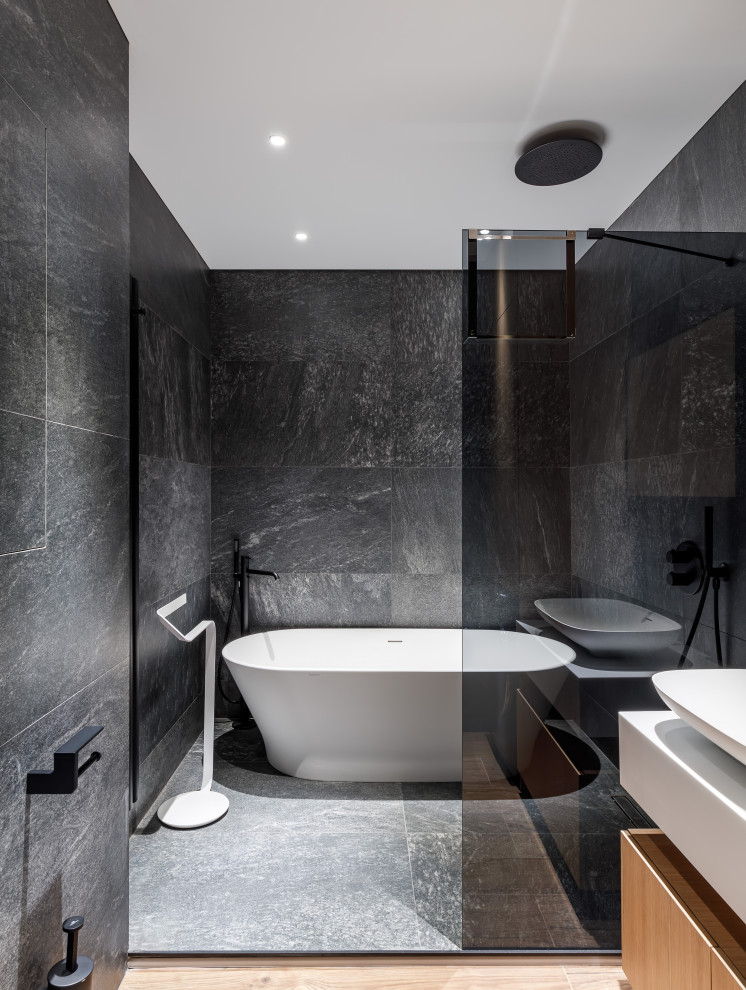 На фото: главная ванная комната в современном стиле с отдельно стоящей ванной, черной плиткой и душевой комнатой с