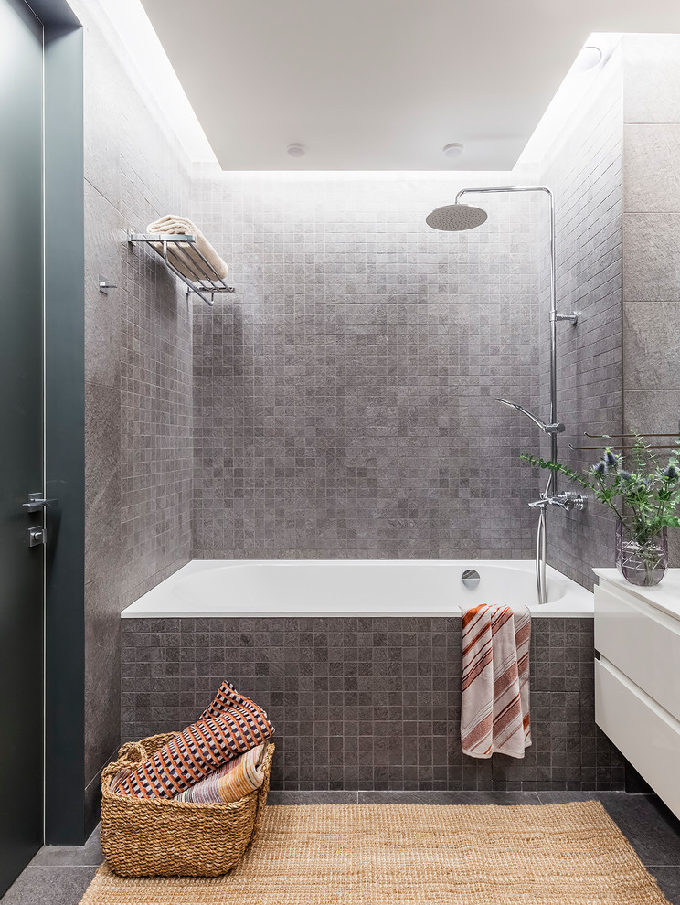 Inspiration for a medium sized contemporary ensuite wet room bathroom in Other with flat-panel cabinets, white cabinets, a submerged bath, a wall mounted toilet, grey tiles, ceramic tiles, grey walls, ceramic flooring, a built-in sink, marble worktops, grey floors, a sliding door and white worktops.