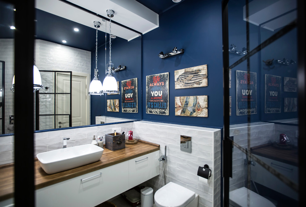 На фото: ванная комната среднего размера в современном стиле с душем в нише, инсталляцией, белой плиткой, керамической плиткой, синими стенами, полом из керамической плитки, душевой кабиной, накладной раковиной, серым полом, душем с распашными дверями и гигиеническим душем с
