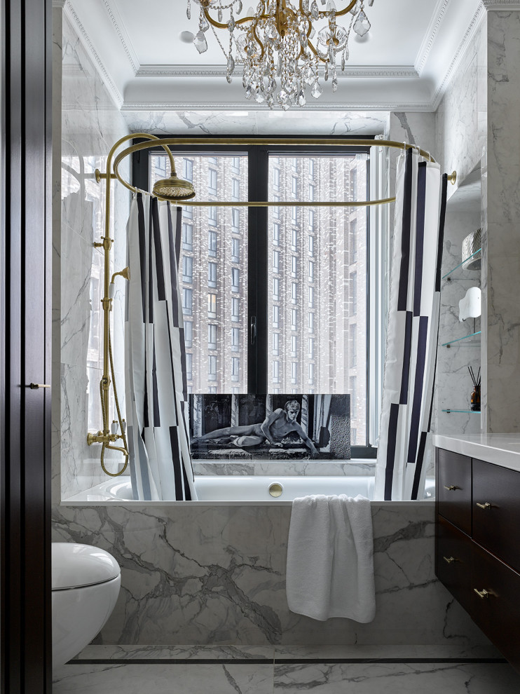 Modern inredning av ett vit vitt en-suite badrum, med släta luckor, ett badkar i en alkov, en dusch/badkar-kombination, en vägghängd toalettstol och grått golv