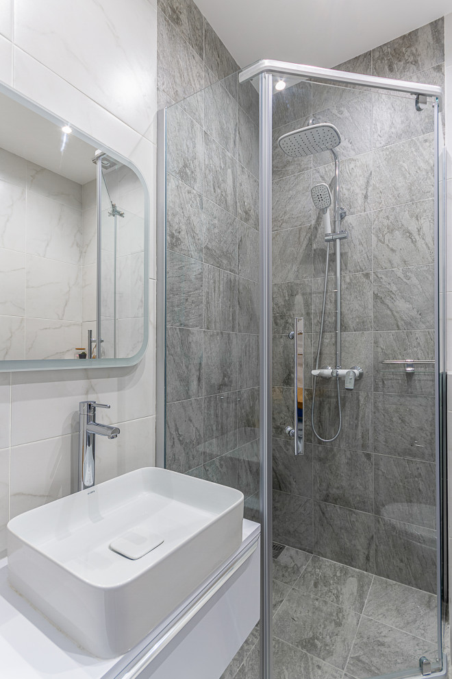 Esempio di una stanza da bagno con doccia contemporanea di medie dimensioni con ante lisce, ante bianche, doccia ad angolo, piastrelle grigie, lavabo a bacinella, pavimento grigio, porta doccia a battente e top bianco