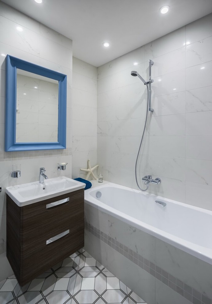 Cette image montre une salle de bain principale design en bois foncé avec un placard à porte plane, une baignoire en alcôve, un combiné douche/baignoire, un carrelage blanc, un lavabo intégré et un sol gris.