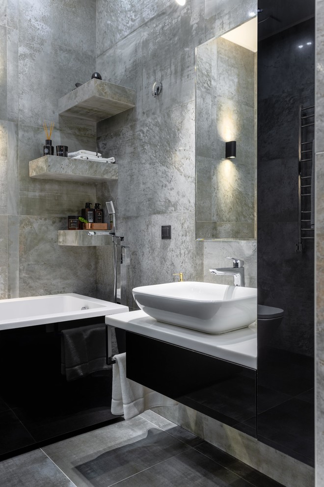 Idéer för ett mellanstort modernt vit en-suite badrum, med svarta skåp, en vägghängd toalettstol, grå kakel, porslinskakel, grå väggar, klinkergolv i porslin, bänkskiva i akrylsten, släta luckor, ett fristående handfat och grått golv