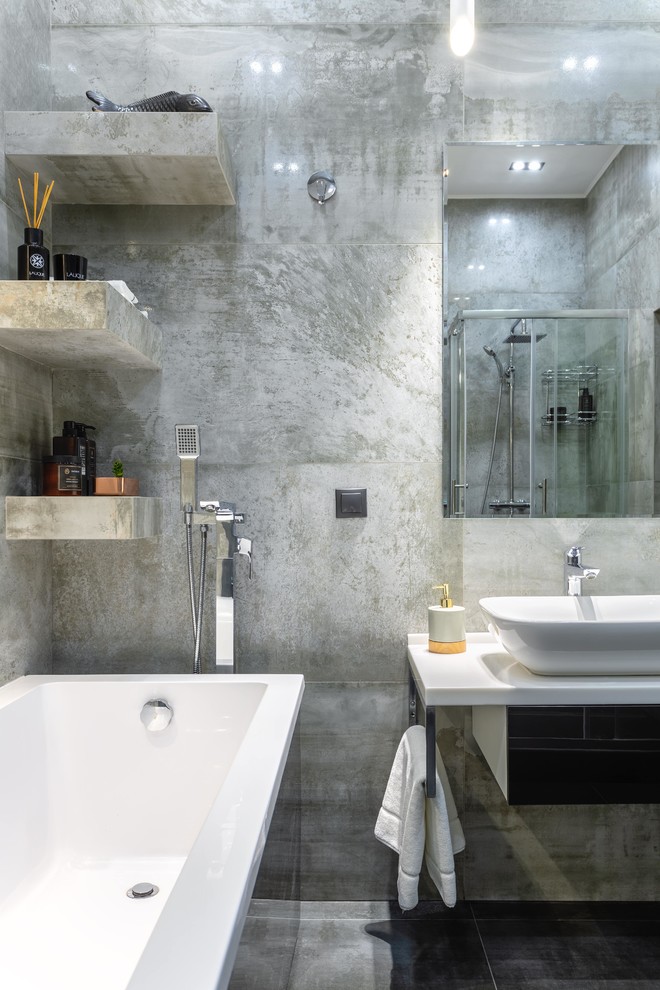 Идея дизайна: ванная комната среднего размера в современном стиле с черными фасадами, отдельно стоящей ванной, душевой комнатой, инсталляцией, серой плиткой, керамогранитной плиткой, серыми стенами, полом из керамогранита, душевой кабиной, накладной раковиной, столешницей из искусственного камня, черным полом, шторкой для ванной и белой столешницей