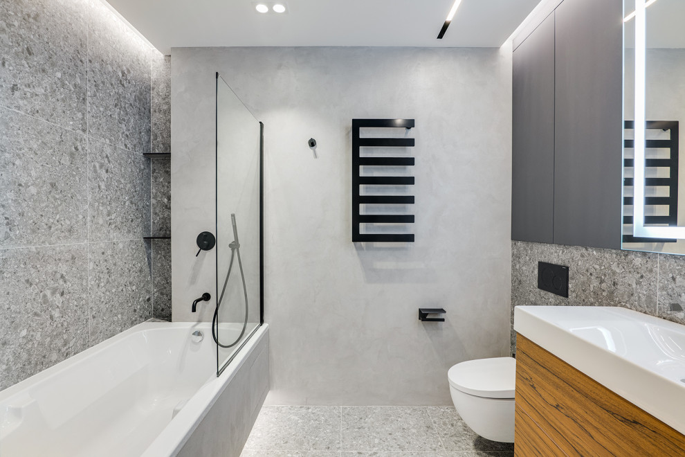 На фото: главная ванная комната в современном стиле с плоскими фасадами, фасадами цвета дерева среднего тона, инсталляцией, серой плиткой и серым полом с