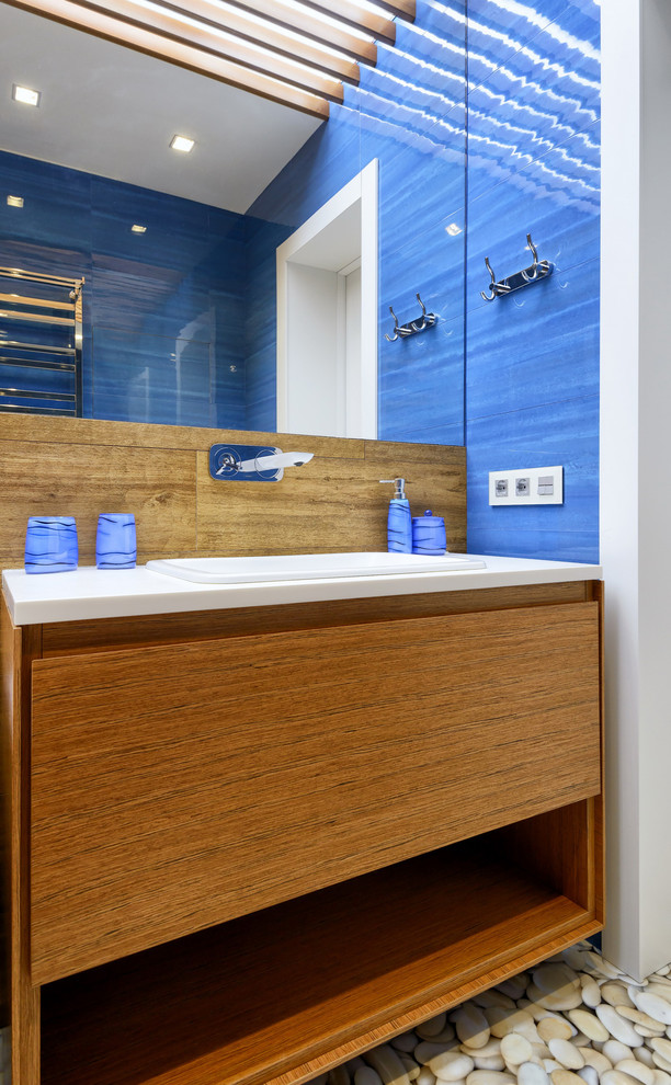 Пример оригинального дизайна: ванная комната в современном стиле с плоскими фасадами, фасадами цвета дерева среднего тона, синими стенами и накладной раковиной