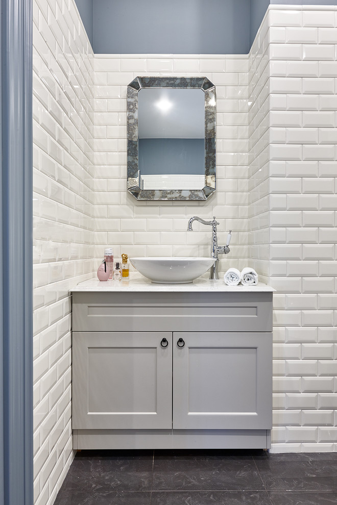 На фото: ванная комната в стиле неоклассика (современная классика) с серыми фасадами, белой плиткой, керамической плиткой, синими стенами, настольной раковиной, черным полом, белой столешницей и фасадами с утопленной филенкой с
