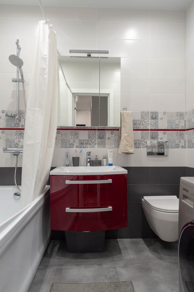 Стильный дизайн: маленькая ванная комната в современном стиле с красными фасадами, полновстраиваемой ванной, инсталляцией, серой плиткой, белыми стенами, полом из керамогранита и серым полом для на участке и в саду - последний тренд