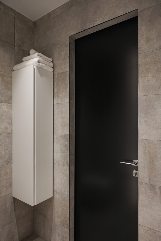 Exemple d'une salle de bain principale tendance de taille moyenne avec un placard à porte plane, des portes de placard blanches, une baignoire encastrée, WC suspendus, un carrelage gris, des carreaux de porcelaine, un mur gris, un sol en carrelage de porcelaine, un lavabo intégré, un plan de toilette en surface solide, un sol gris, un plan de toilette blanc, meuble simple vasque et meuble-lavabo suspendu.