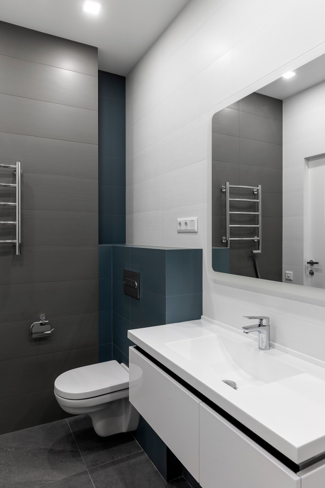 Ispirazione per una stanza da bagno con doccia contemporanea di medie dimensioni con ante lisce, ante bianche, WC sospeso, pareti blu, pavimento in gres porcellanato, lavabo integrato, pavimento grigio e top bianco