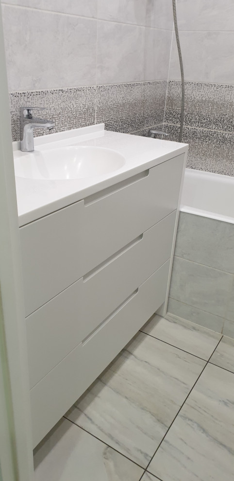 Small contemporary ensuite bathroom in Moscow with recessed-panel cabinets, white cabinets, a built-in bath, grey tiles, ceramic tiles, grey walls, porcelain flooring, solid surface worktops, grey floors, white worktops, a wall niche, a single sink and a freestanding vanity unit.
