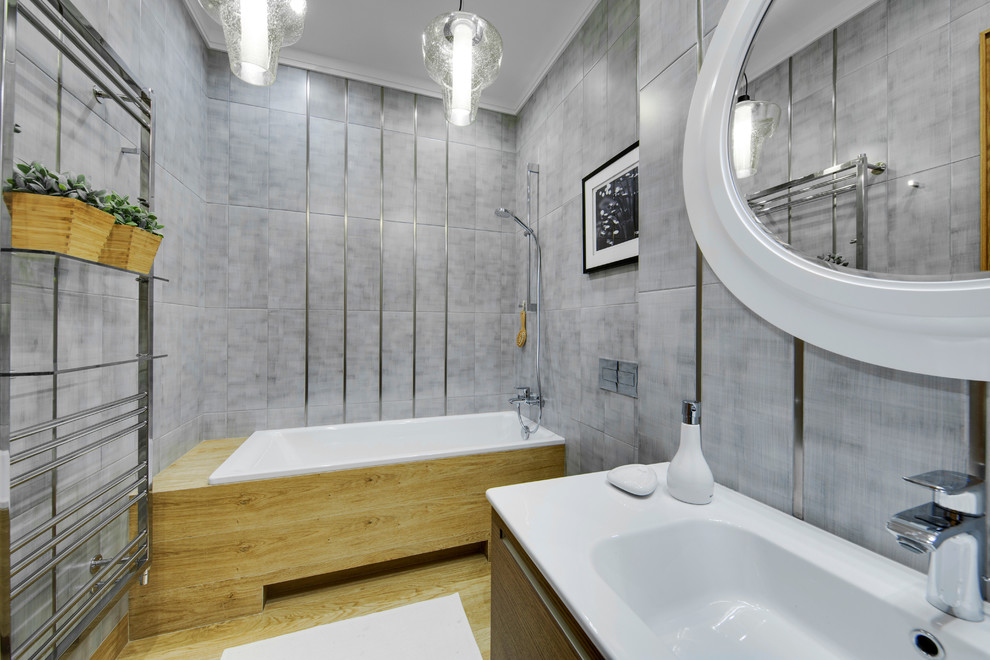 Immagine di una stanza da bagno design con vasca ad alcova e piastrelle grigie
