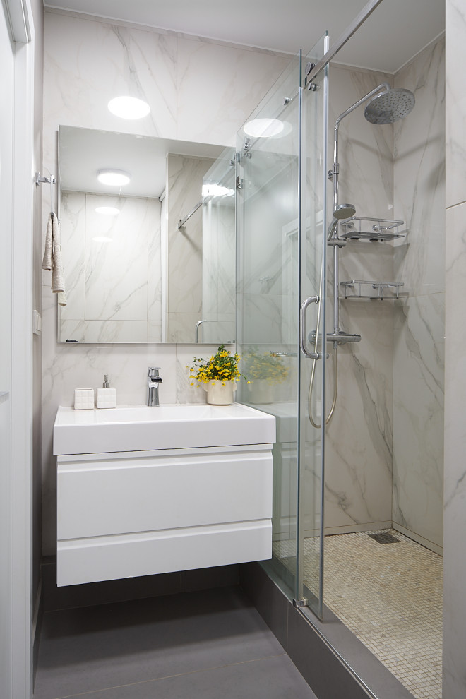 Foto på ett mellanstort funkis vit badrum med dusch, med släta luckor, vita skåp, en dusch i en alkov, grå kakel, porslinskakel, klinkergolv i porslin, ett integrerad handfat, grått golv och dusch med gångjärnsdörr