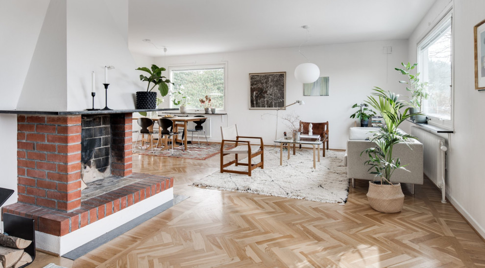 Стильный дизайн: гостиная комната в скандинавском стиле с стандартным камином и фасадом камина из кирпича - последний тренд