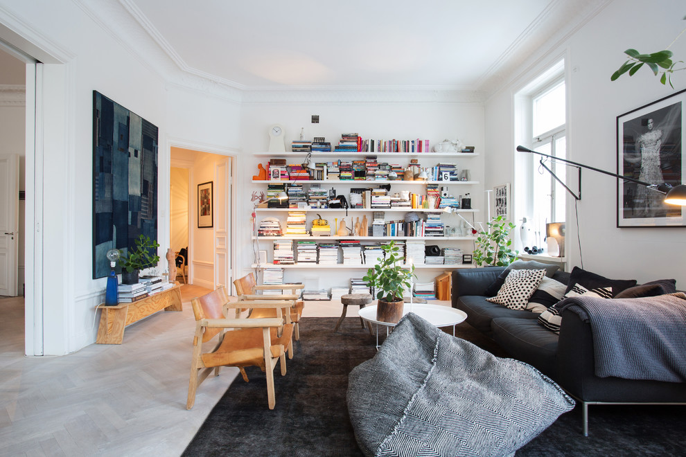 Bild på ett mellanstort minimalistiskt allrum med öppen planlösning, med ett bibliotek, vita väggar och ljust trägolv