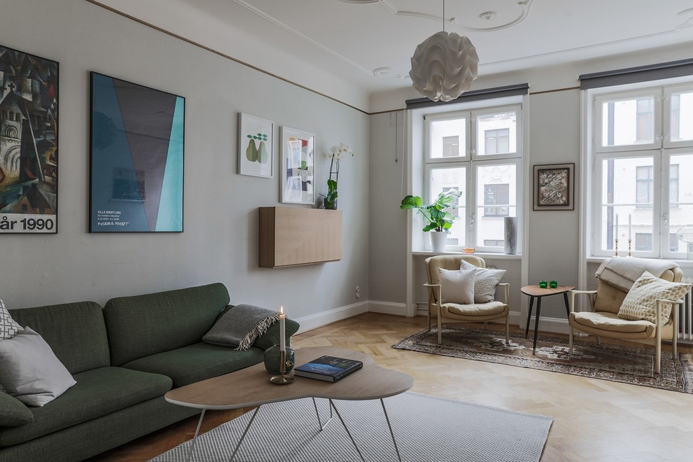На фото: гостиная комната в скандинавском стиле с серыми стенами, светлым паркетным полом и бежевым полом с