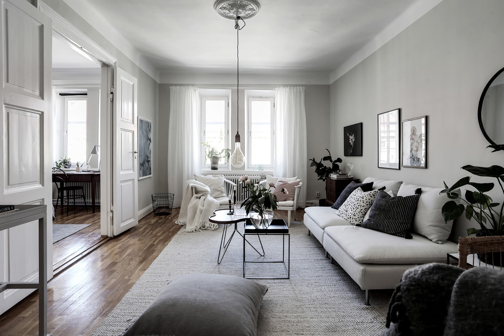 Mittelgroßes, Abgetrenntes Nordisches Wohnzimmer ohne Kamin mit weißer Wandfarbe, braunem Holzboden und braunem Boden in Göteborg