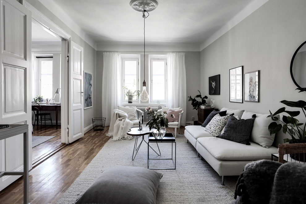 Example of a mid-sized danish enclosed medium tone wood floor and brown floor living room design in Gothenburg with white walls and no fireplace