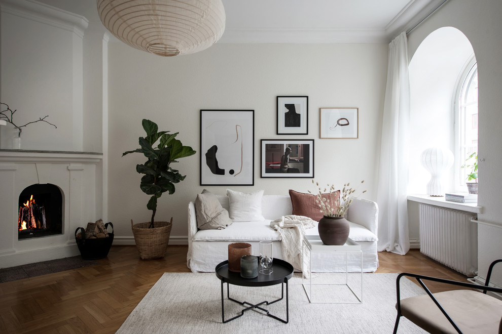 Idéer för ett skandinaviskt separat vardagsrum, med vita väggar, mellanmörkt trägolv, en standard öppen spis, en spiselkrans i gips och brunt golv