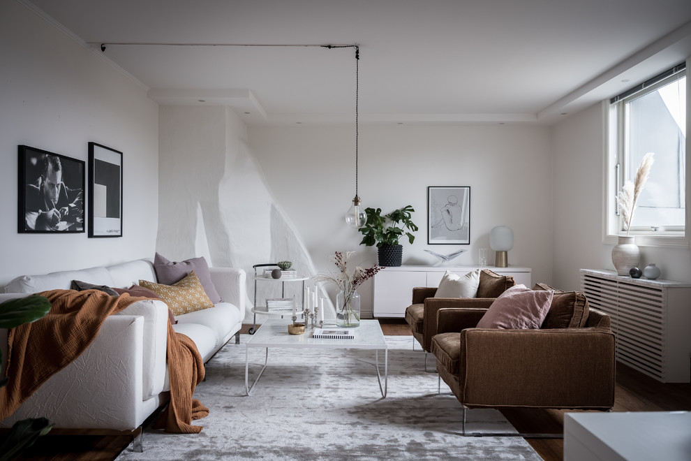 This is an example of a scandi enclosed living room in Gothenburg with white walls, medium hardwood flooring and brown floors.