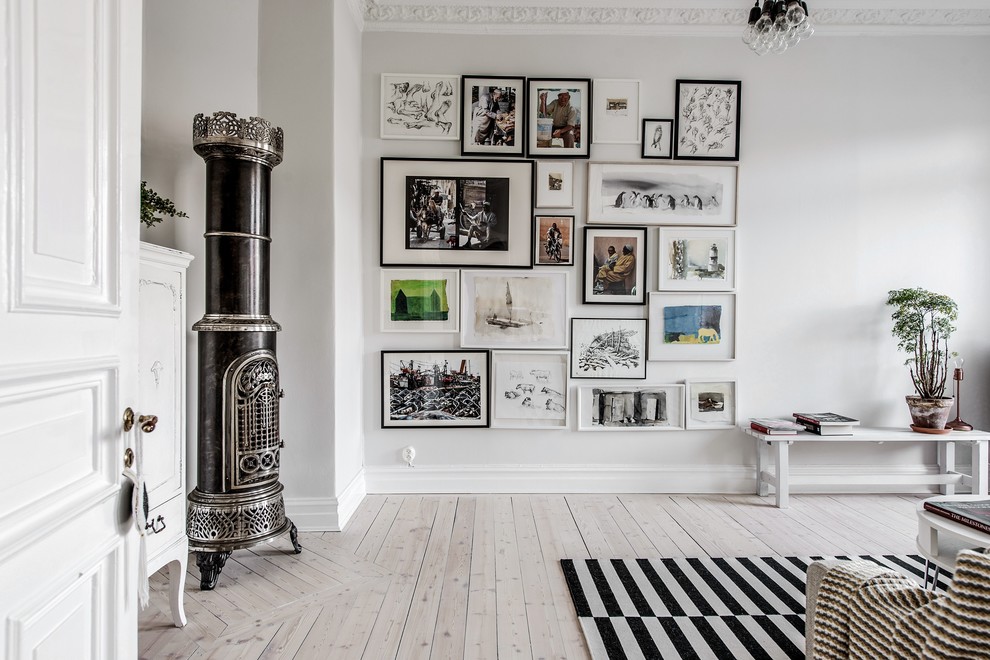 Nordisches Wohnzimmer mit weißer Wandfarbe, hellem Holzboden, Kaminofen, Kaminumrandung aus Metall und beigem Boden in Göteborg