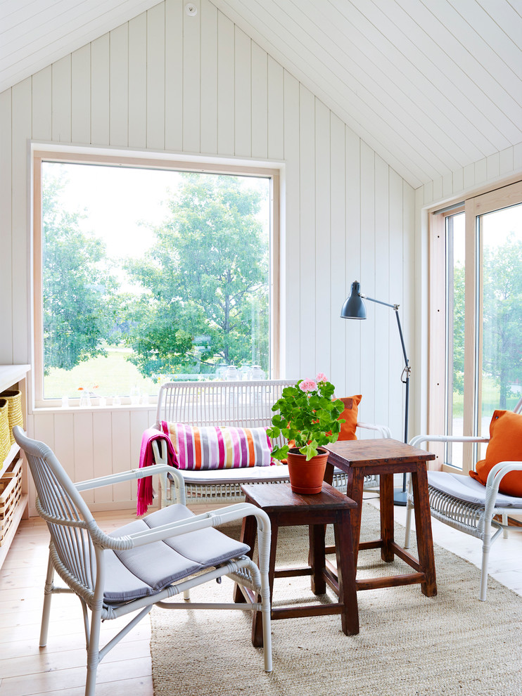 This is an example of a small scandi open plan living room in Stockholm with white walls and light hardwood flooring.