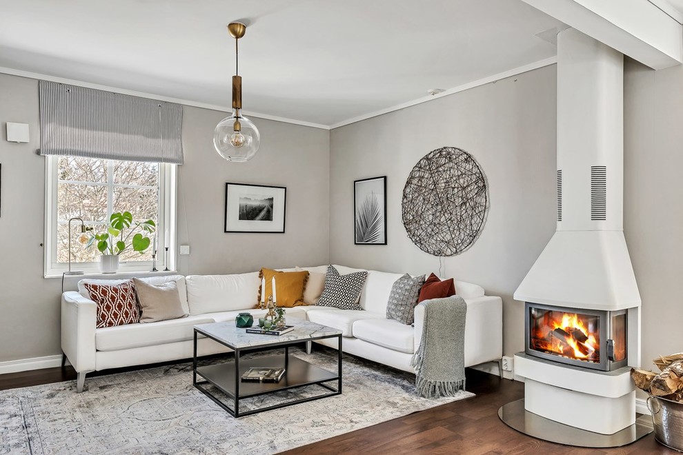 Inspiration för mellanstora nordiska separata vardagsrum, med grå väggar, mellanmörkt trägolv, brunt golv, en dubbelsidig öppen spis och en spiselkrans i metall