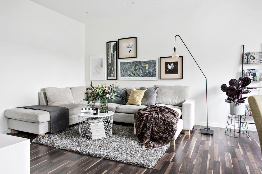 Exempel på ett mellanstort minimalistiskt allrum med öppen planlösning, med mörkt trägolv, brunt golv och vita väggar