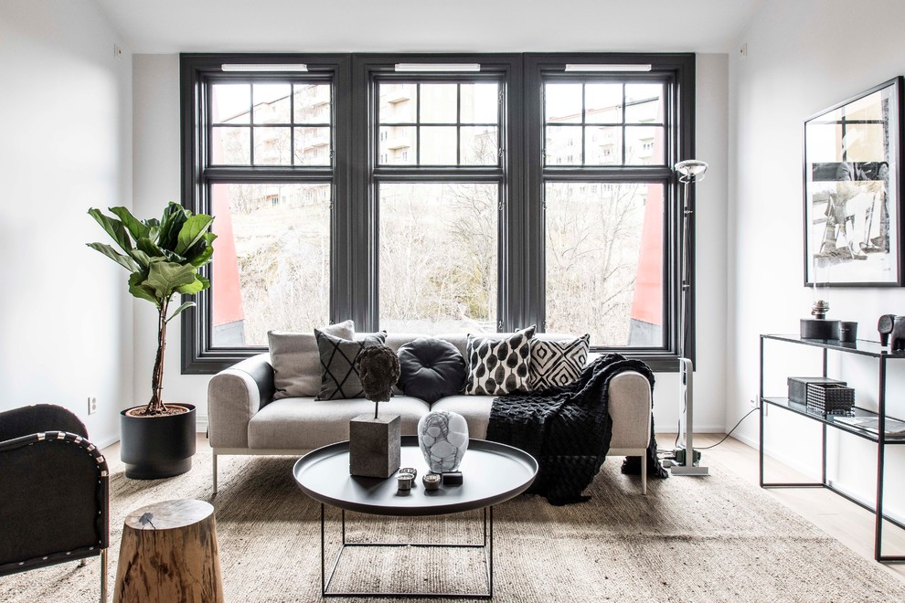 This is an example of an industrial formal enclosed living room in Stockholm with white walls and light hardwood flooring.