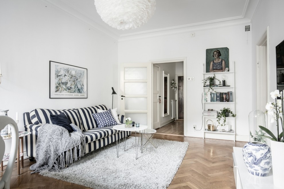 Imagen de salón para visitas abierto escandinavo de tamaño medio sin chimenea con paredes blancas, suelo de madera en tonos medios y televisor colgado en la pared