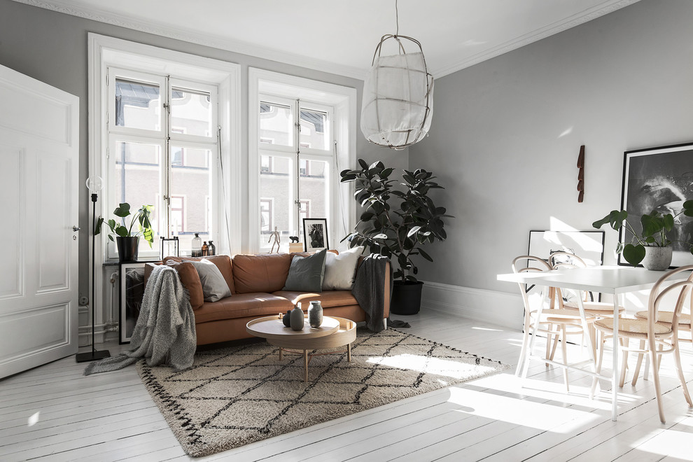 Großes Nordisches Wohnzimmer mit grauer Wandfarbe, gebeiztem Holzboden und weißem Boden in Stockholm