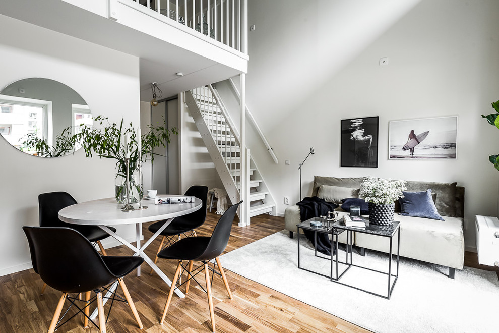Example of a danish medium tone wood floor and brown floor living room design in Stockholm with white walls
