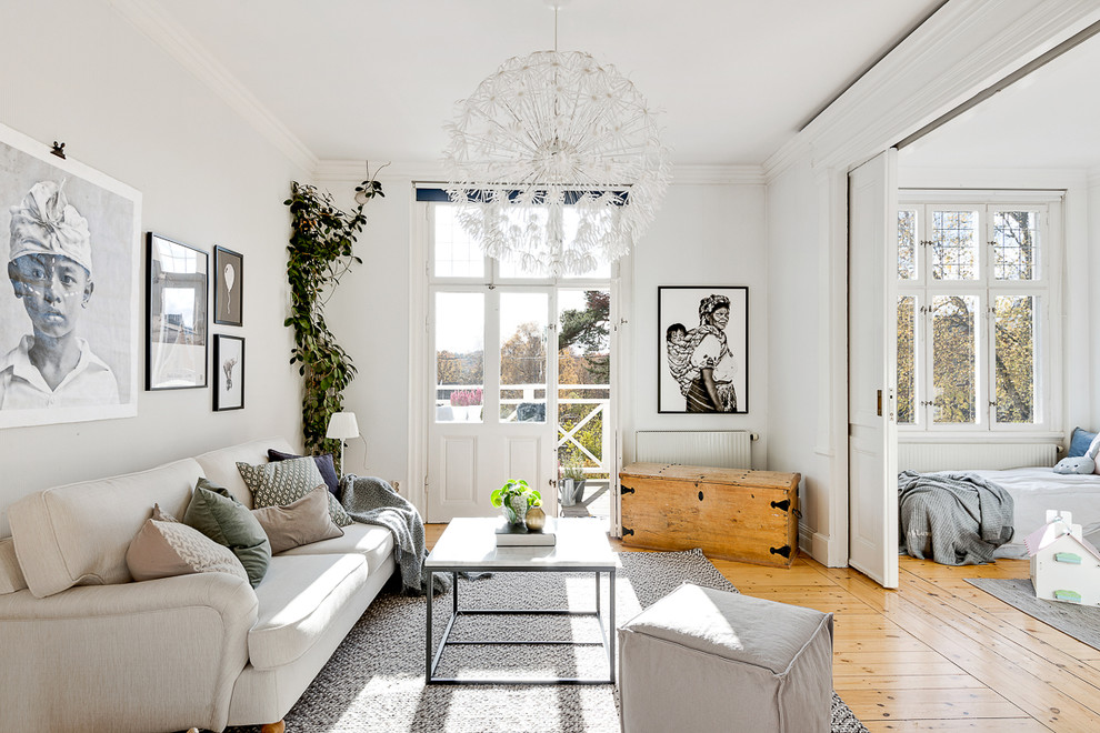 Photo of a medium sized scandinavian open plan living room in Stockholm with white walls, medium hardwood flooring and no tv.