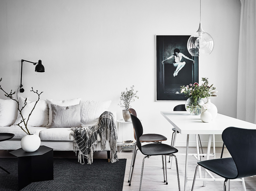 Exempel på ett minimalistiskt vardagsrum, med vita väggar och ljust trägolv