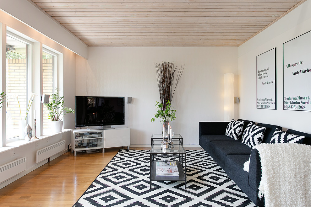 Abgetrenntes, Großes, Repräsentatives Nordisches Wohnzimmer mit weißer Wandfarbe, braunem Holzboden und freistehendem TV in Sonstige
