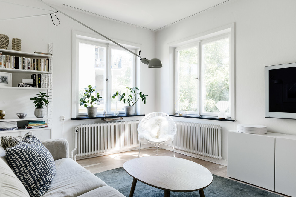 Nordisk inredning av ett mellanstort vardagsrum, med ett finrum, vita väggar, ljust trägolv och en väggmonterad TV