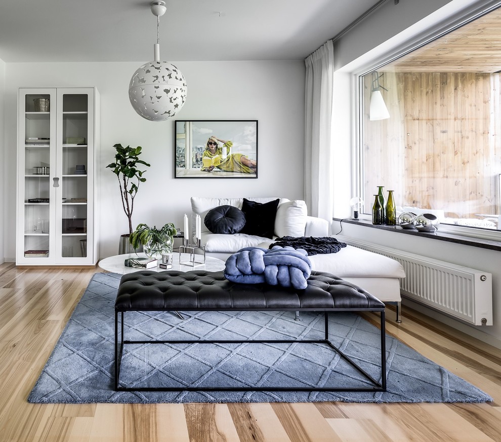 Offenes Skandinavisches Wohnzimmer ohne Kamin mit weißer Wandfarbe und hellem Holzboden in Stockholm