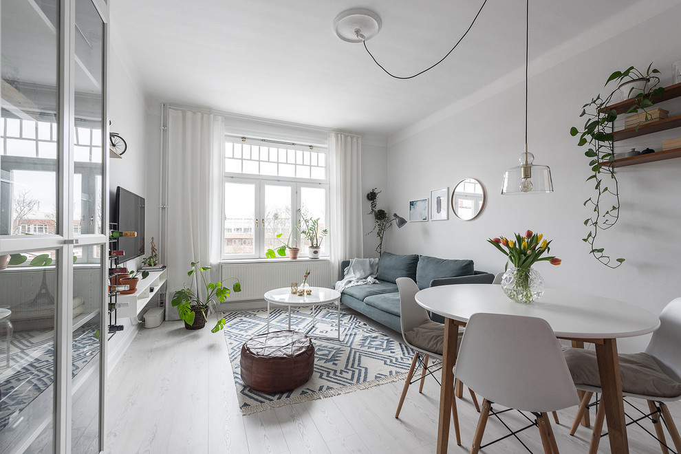 На фото: гостиная комната среднего размера в скандинавском стиле с белыми стенами, полом из ламината и белым полом с