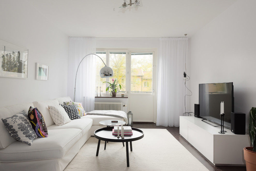 Mittelgroßes, Abgetrenntes Skandinavisches Wohnzimmer ohne Kamin mit weißer Wandfarbe, dunklem Holzboden, freistehendem TV und braunem Boden in Stockholm