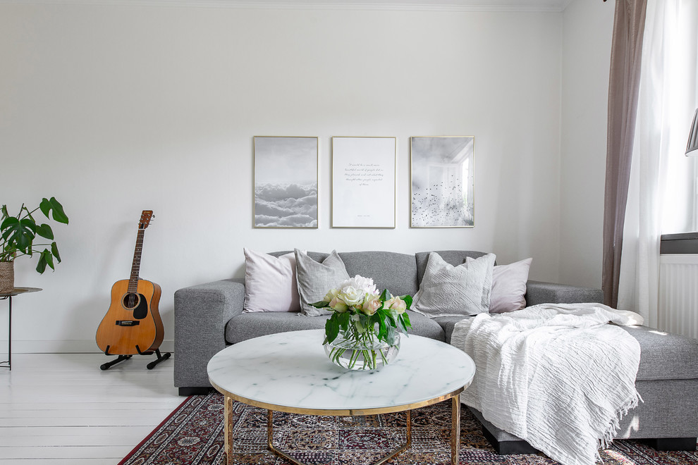Minimalistisk inredning av ett mellanstort vardagsrum, med vita väggar, målat trägolv och vitt golv