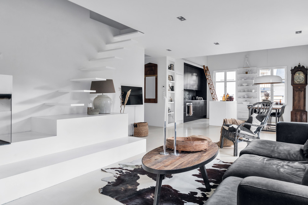 Идея дизайна: открытая гостиная комната в современном стиле с белыми стенами, бетонным полом, телевизором на стене и белым полом
