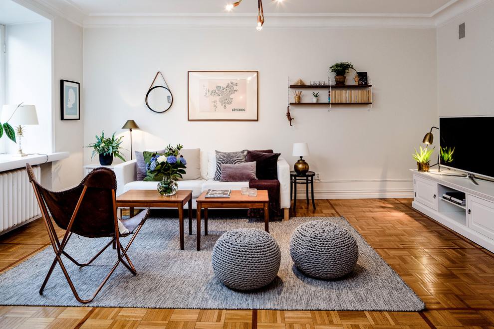 Repräsentatives, Großes, Offenes Skandinavisches Wohnzimmer ohne Kamin mit weißer Wandfarbe, braunem Holzboden und freistehendem TV in Göteborg