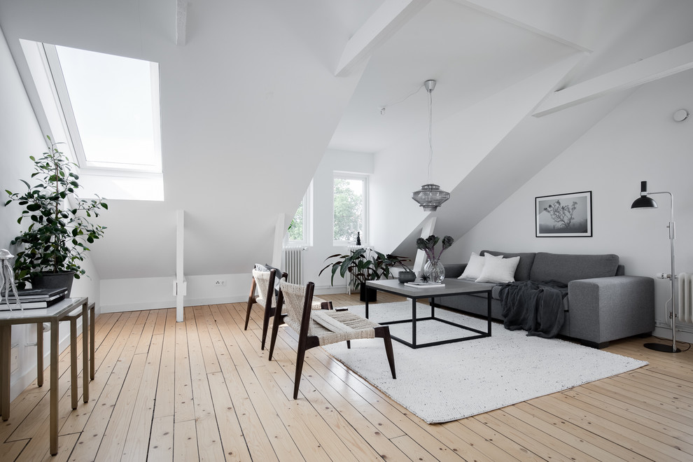 Foto på ett mellanstort nordiskt loftrum, med vita väggar, ljust trägolv, beiget golv och ett finrum