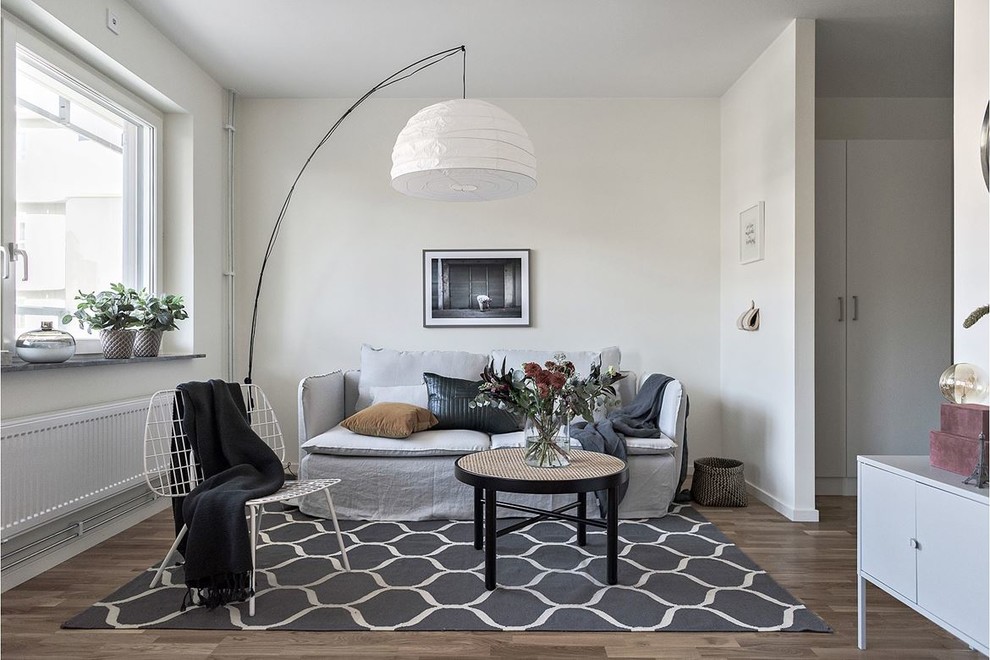 Стильный дизайн: гостиная комната среднего размера в скандинавском стиле с белыми стенами, паркетным полом среднего тона и коричневым полом - последний тренд