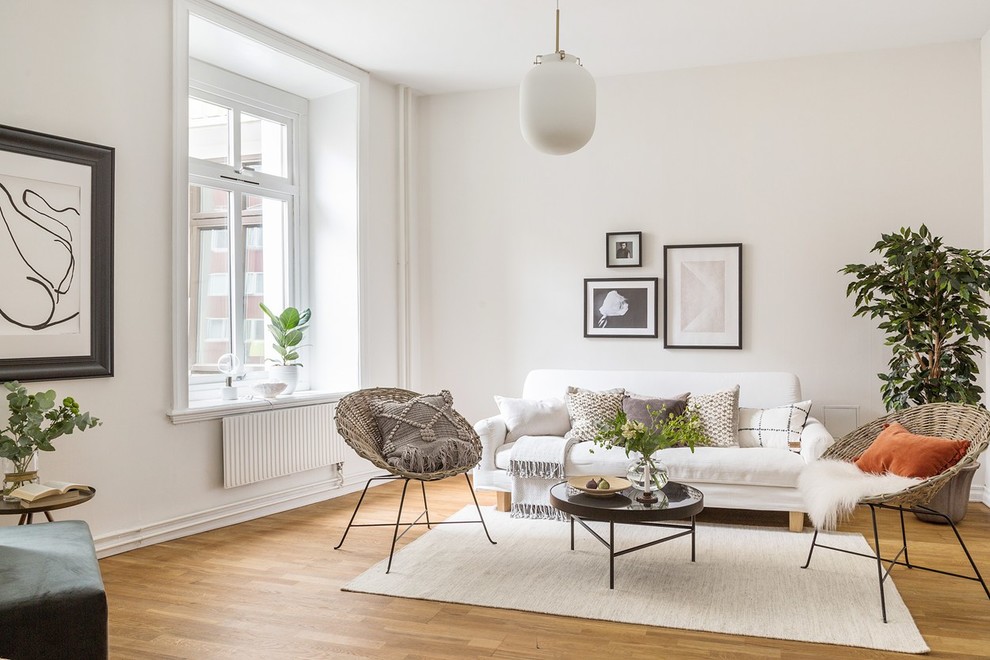 Abgetrenntes Skandinavisches Wohnzimmer mit weißer Wandfarbe und braunem Holzboden in Göteborg